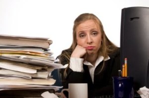 fed-up-woman-with-pile-of-paper-at-desk